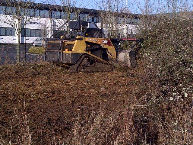 Commercial site clearance machinery clearing overgrown vegetation and outdoor land