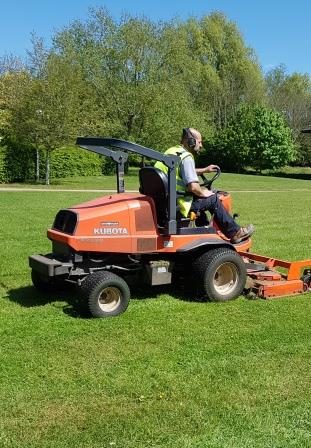 Commercial grounds maintenance tractor mower working on a maintained grass area in Swindon